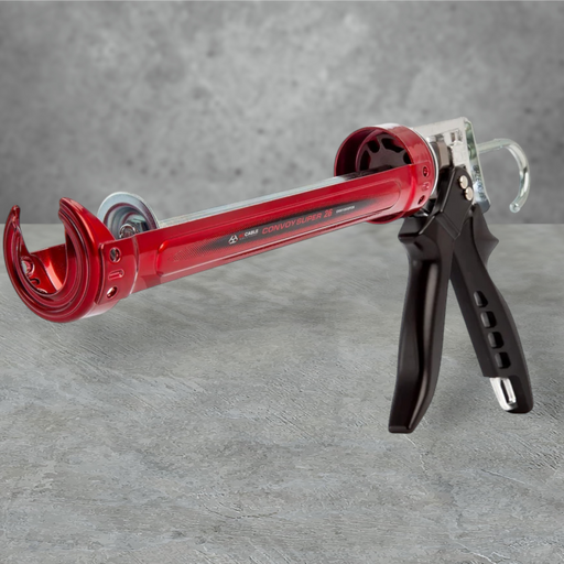 Red skeleton caulking gun with a black trigger handle, resting on a grey concrete surface.
